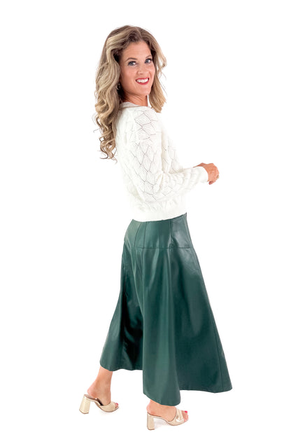 Side view of woman wearing Hunter Green Faux Leather Midi Skirt with top against white studio background.