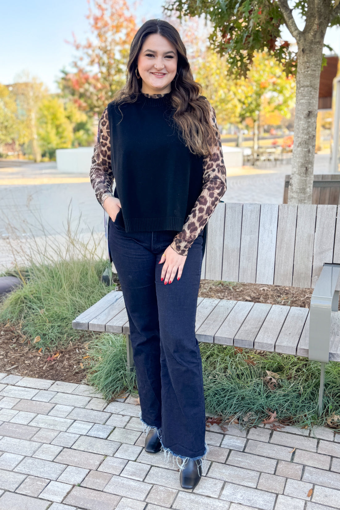 Front view of woman wearing Black sweater and Leopard Mesh Top with jeans while outside.