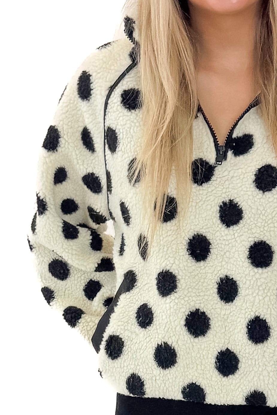 Front detail view of woman wearing Ivory &amp; Black Polka Dot Sherpa Half Zip Sweatshirt with jeans against white studio background.