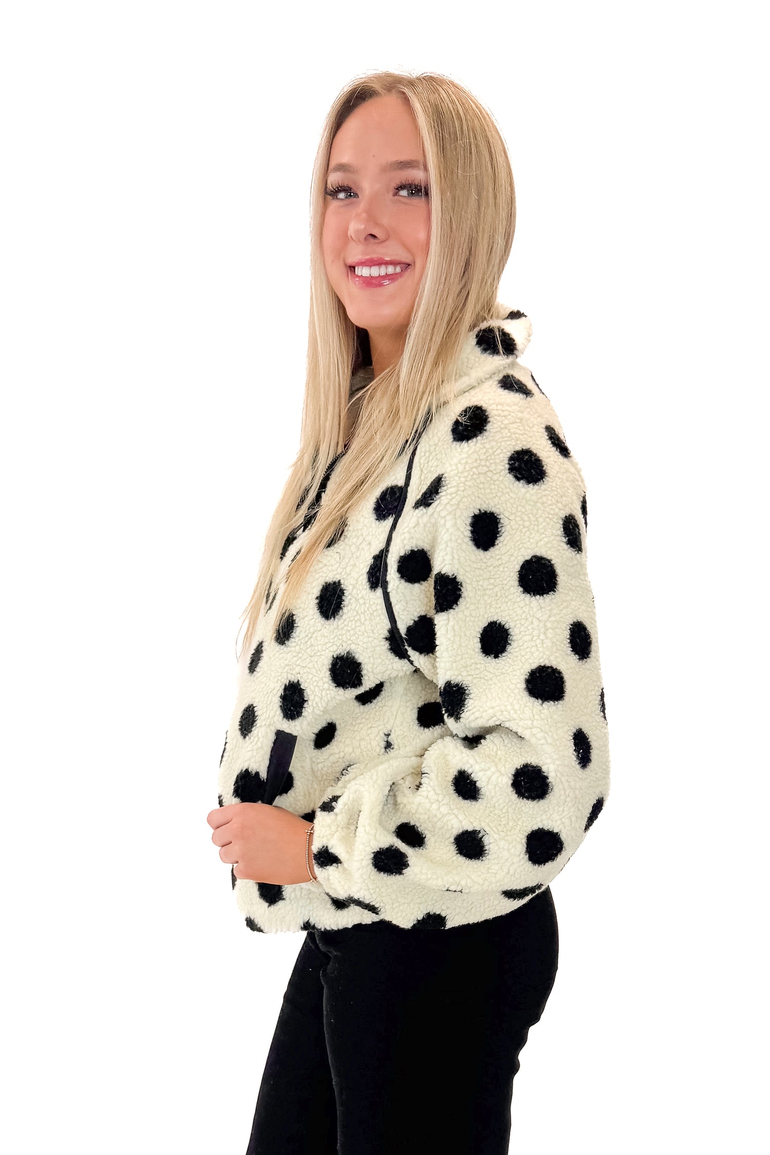 Front side view of woman wearing Ivory &amp; Black Polka Dot Sherpa Half Zip Sweatshirt with jeans against white studio background.