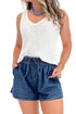 Front detail view of woman wearing Swagger Boutique’s Indigo Denim Shorts With Elastic Waist with top against white studio background.