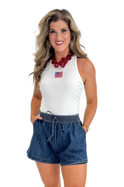 Front view of woman wearing Swagger Boutique’s Indigo Denim Shorts With Elastic Waist with top against white studio background.