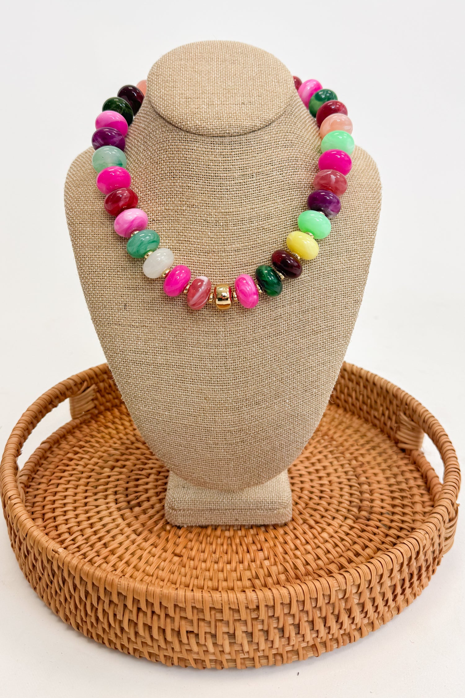 Colorful beaded necklace on a beige jewelry display with a woven base.