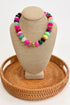 Colorful beaded necklace on a beige jewelry display with a woven base.