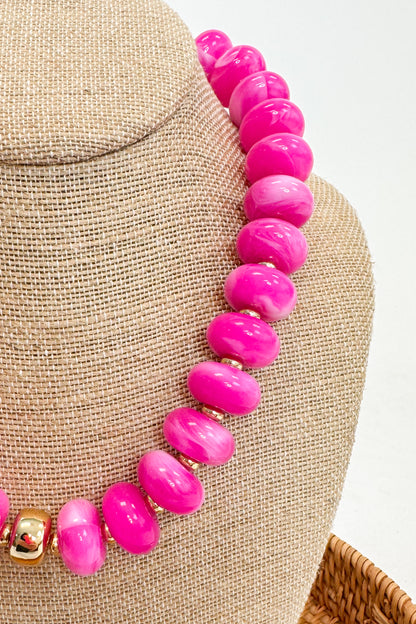 Necklace with pink beads on a mannequin bust against a neutral background