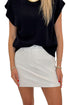 Front view of woman wearing Swagger Boutique’s Ivory Faux Leather Mini Skirt with black sweater against white studio background.