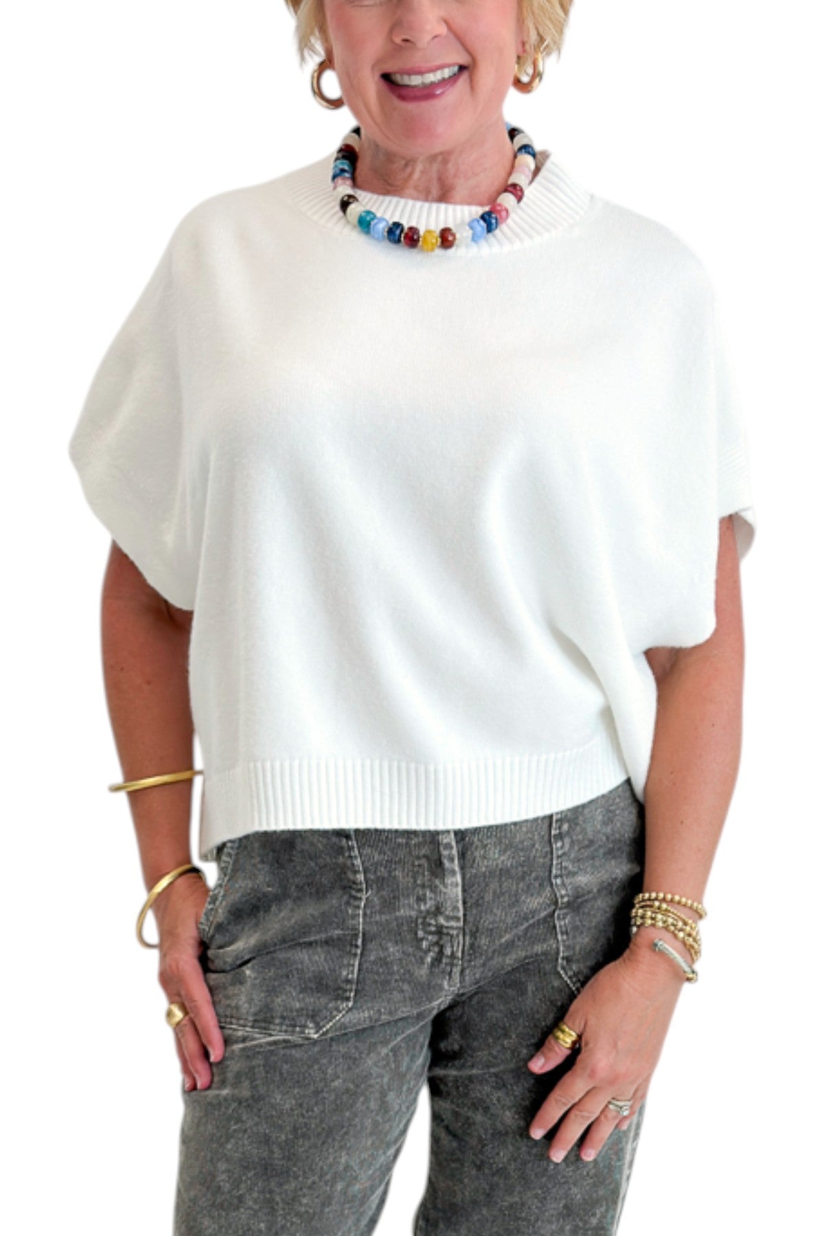 Front detail view of woman wearing Swagger Boutique’s Ivory Light Weight Short Sleeve Sweater with jeans against white studio background.