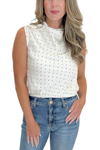 Front detail view of woman wearing Swagger Boutique’s Ivory Polka Dot Sleeveless Top with jeans against white studio background.