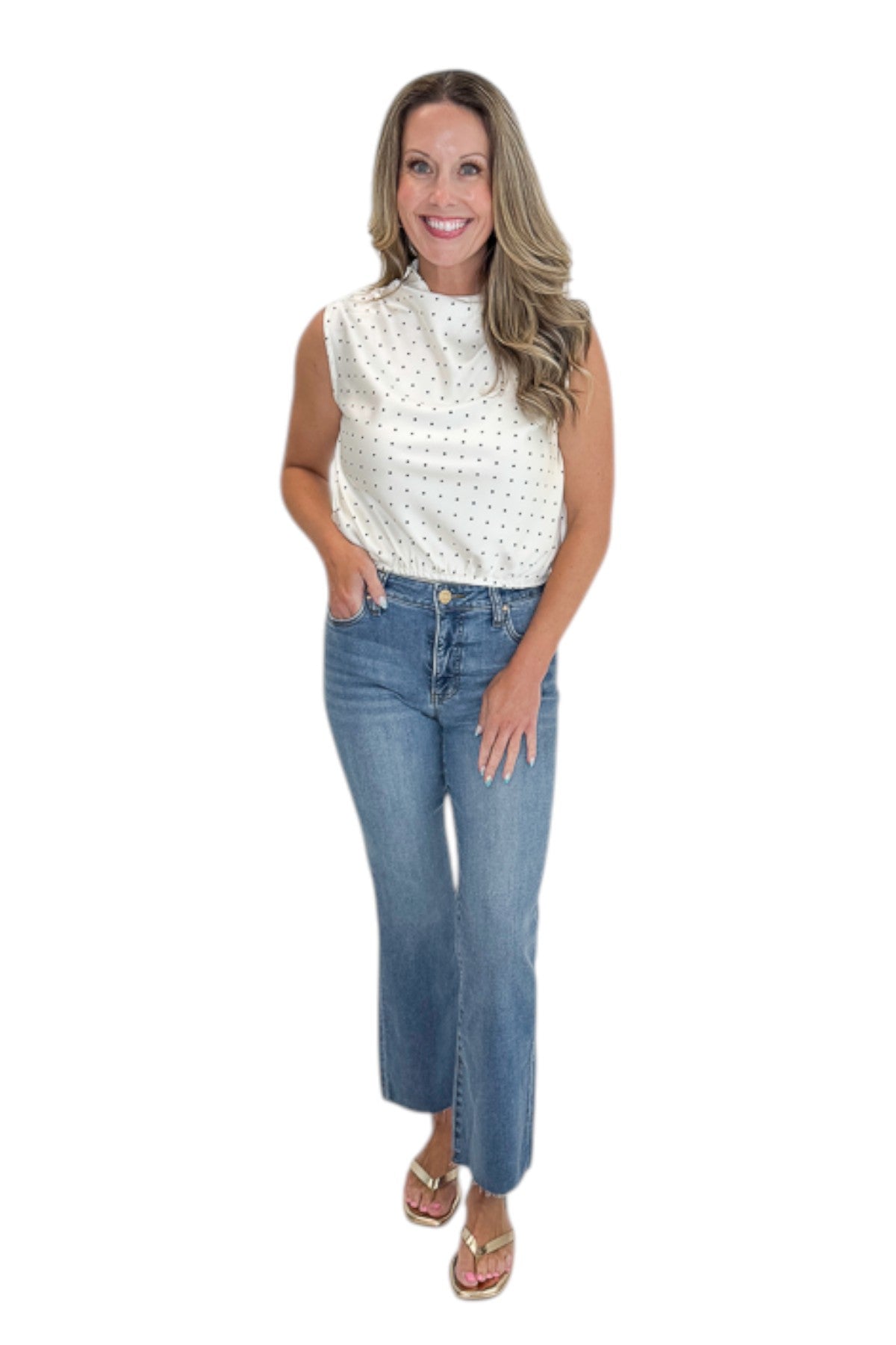 Front view of woman wearing Swagger Boutique’s Ivory Polka Dot Sleeveless Top with jeans against white studio background.