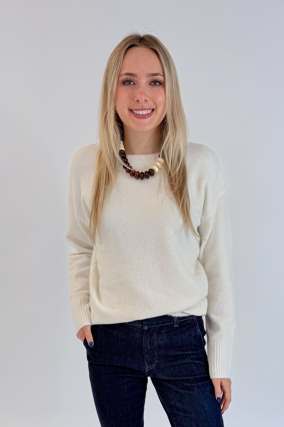 Front view of woman wearing Swagger Boutique’s Ivory Ribbed Hem Sweater with jeans against white studio background.