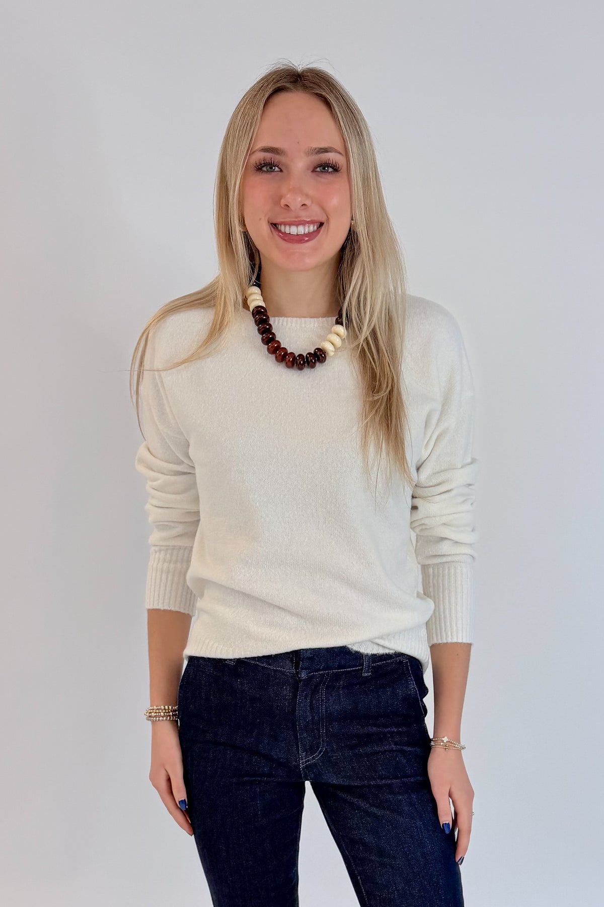 Front view of woman wearing Swagger Boutique’s Ivory Ribbed Hem Sweater with jeans against white studio background.