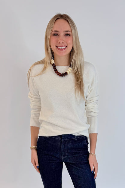 Front view of woman wearing Swagger Boutique’s Ivory Ribbed Hem Sweater with jeans against white studio background.