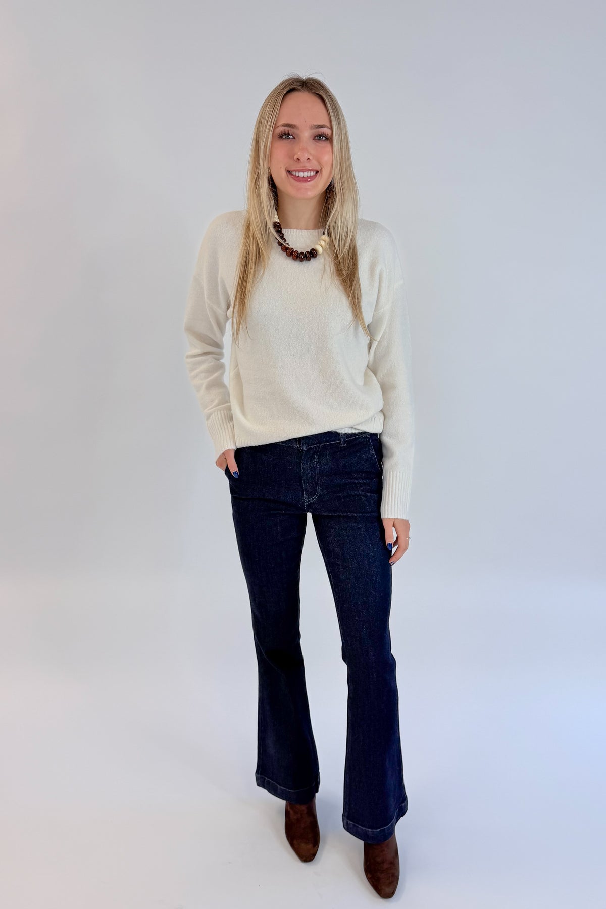 Front view of woman wearing Swagger Boutique’s Ivory Ribbed Hem Sweater with jeans against white studio background.