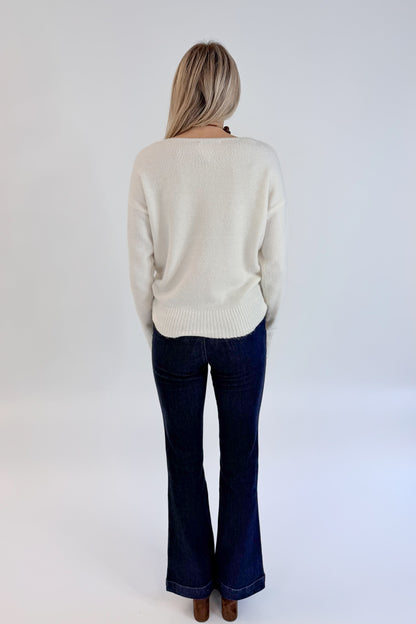 Back view of woman wearing Swagger Boutique’s Ivory Ribbed Hem Sweater with jeans against white studio background.