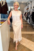 Front view of woman wearing Swagger Boutique’s Ivory Satin Lace Sleeveless Top with Ivory Satin Lace Midi Skirt standing at the store.