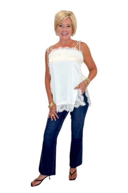 Front view of woman wearing Swagger Boutique’s Ivory Satin Lace Trim Tank Top by Entro with jeans against white studio background.