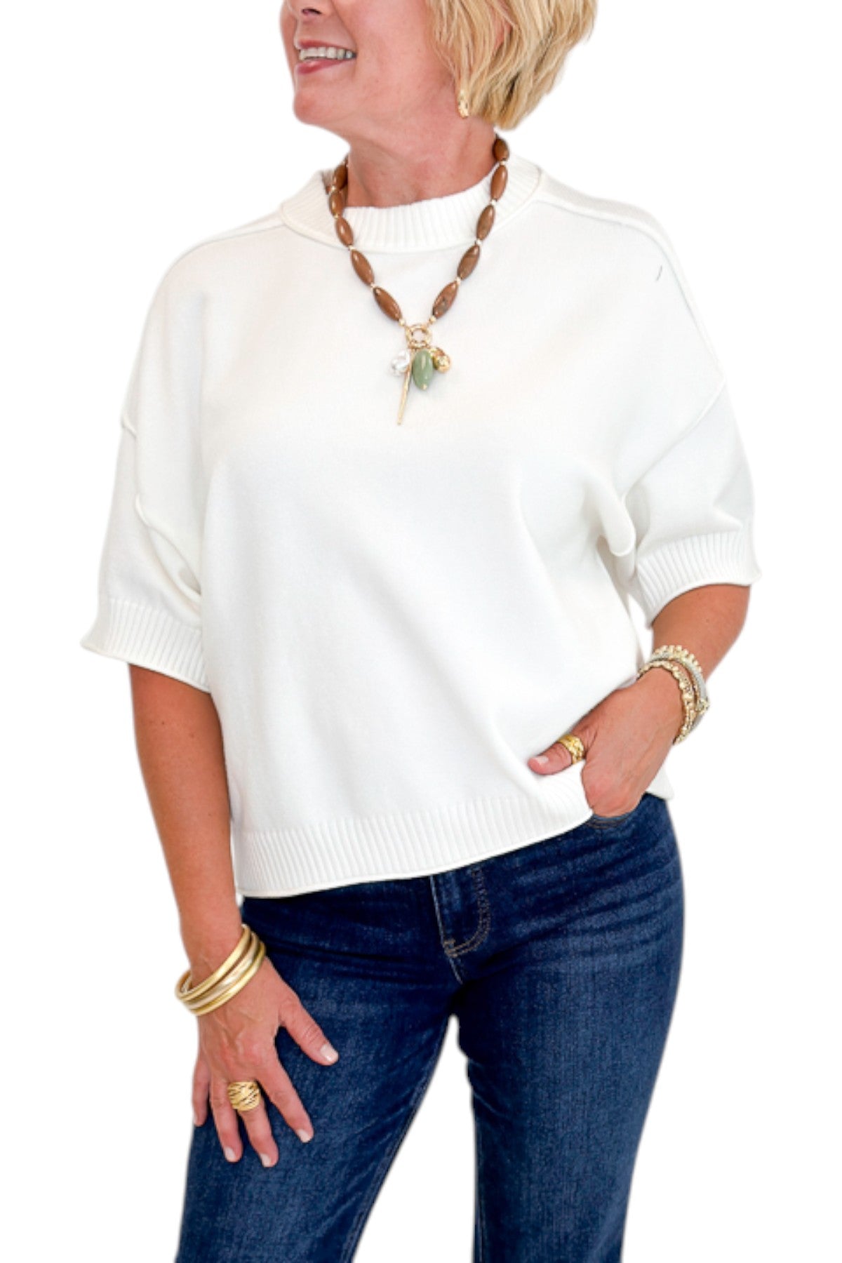 Front detail view of woman wearing Swagger Boutique’s Ivory Short Sleeve Sweater with jeans against white studio background.