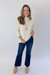 Front view of woman wearing Swagger Boutique’s Ivory Turtleneck Sweater with jeans against white studio background.