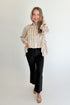 Front view of woman wearing Swagger Boutique’s Ivory & Black Striped Satin Top with jeans against white studio background.