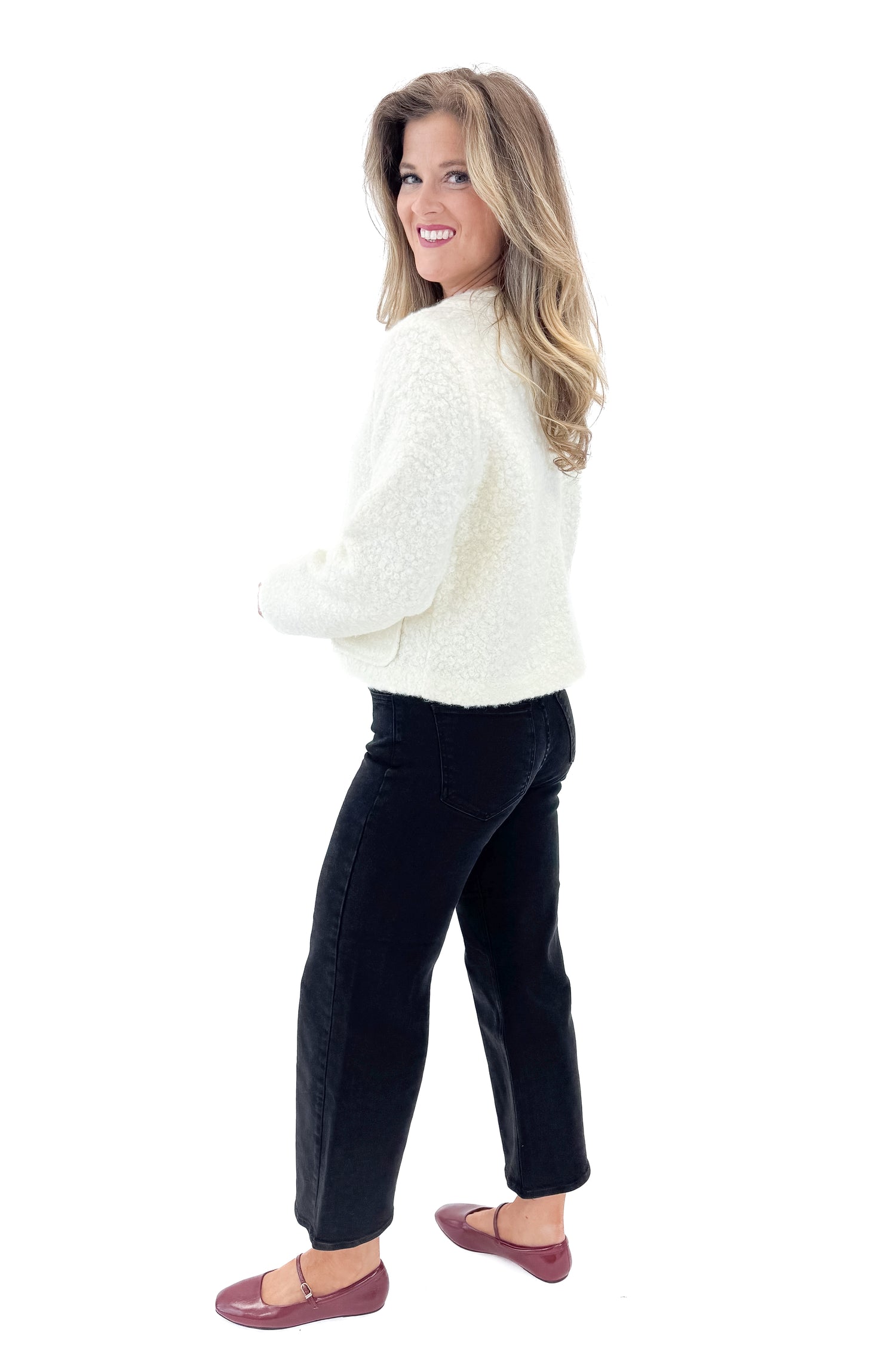 Side view of woman wearing Cream Sherpa Button Up Jacket with jeans against white studio background.