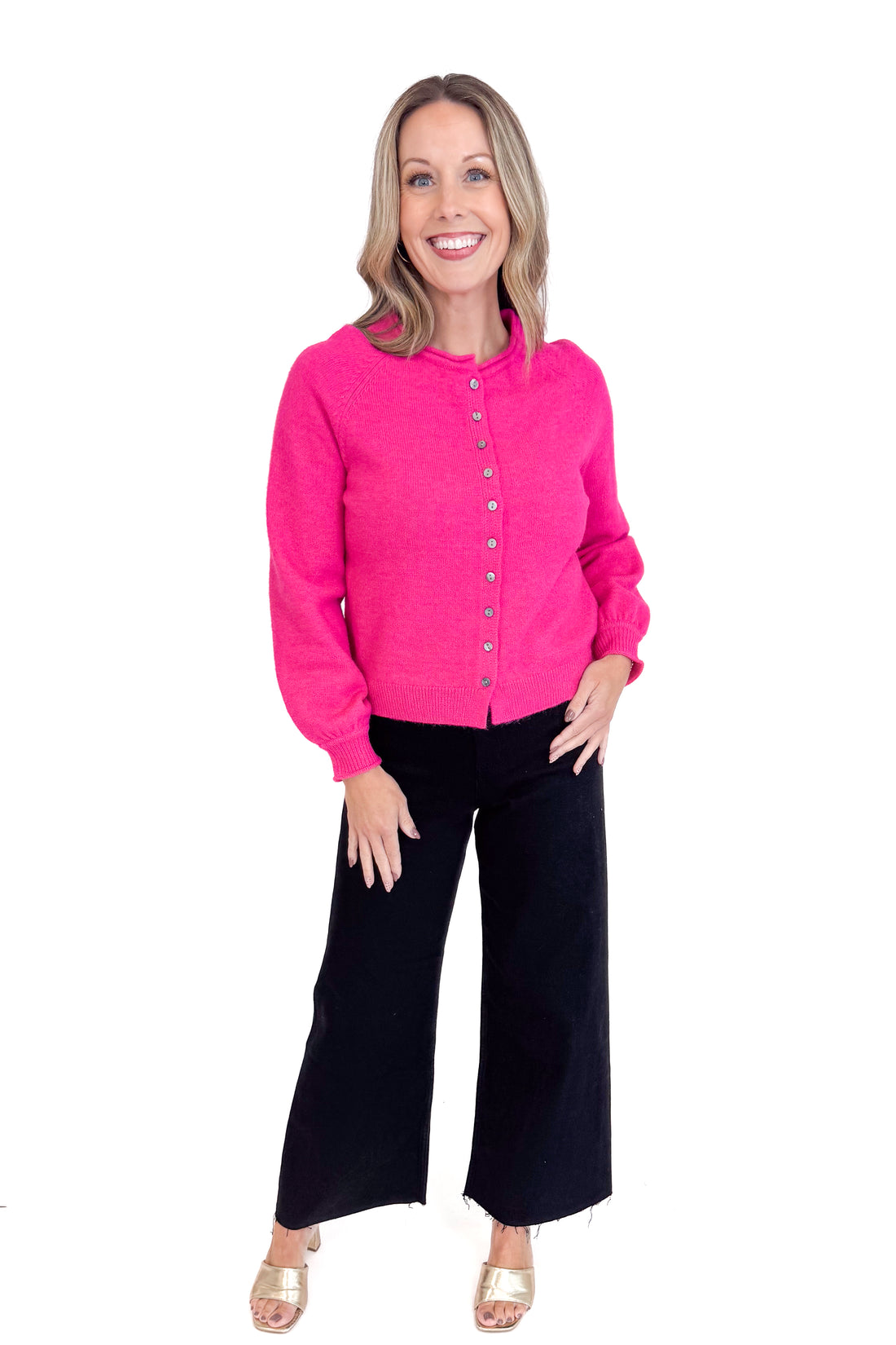Woman wearing a pink cardigan and black pants on a white background