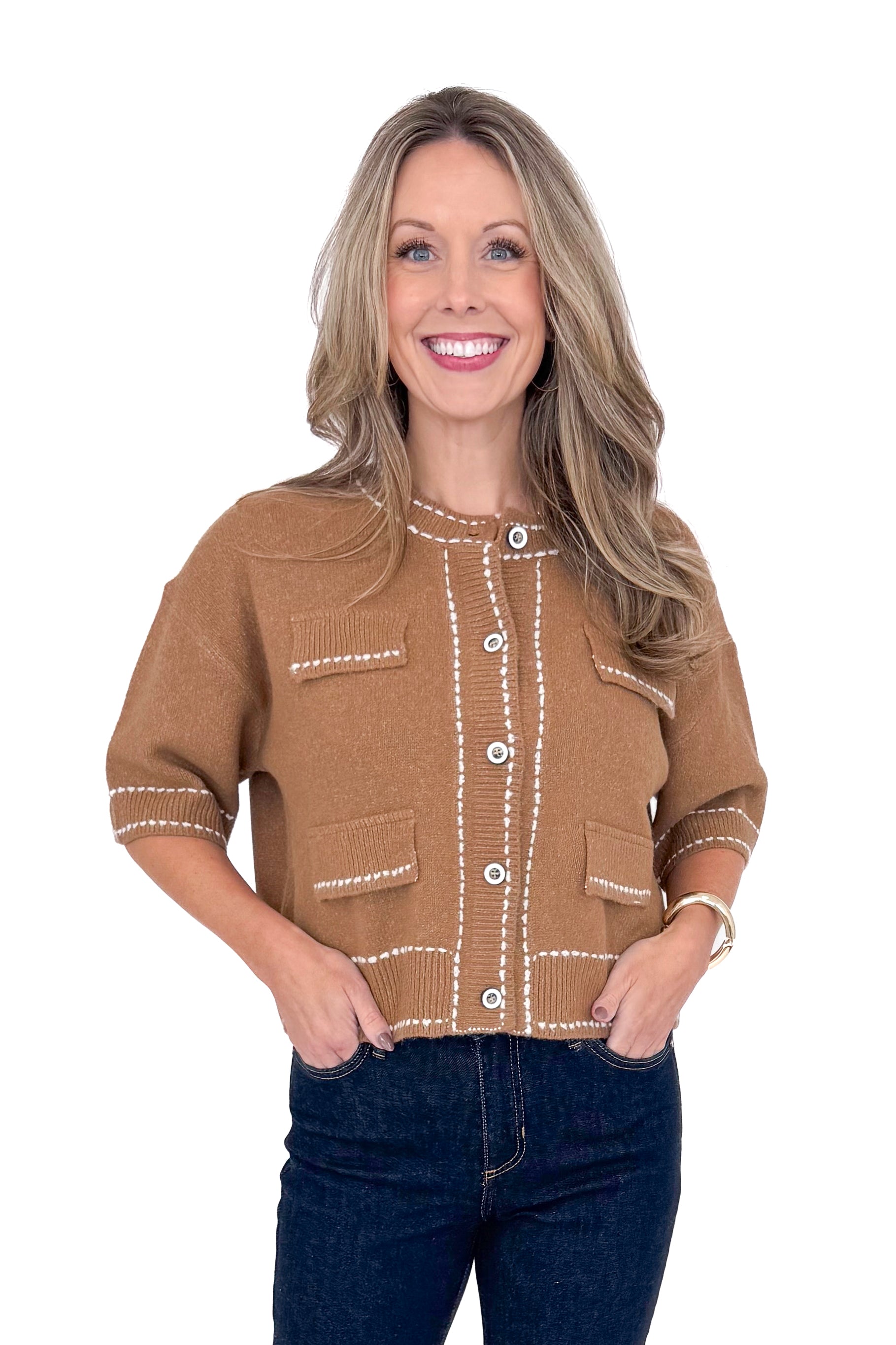 Front view of woman wearing camel stitch detail sweater with jeans against white studio background.