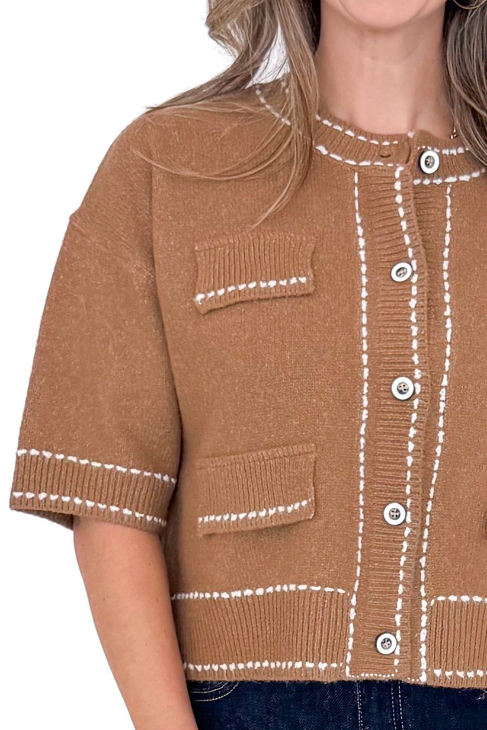 Front detail view of woman wearing camel stitch detail sweater with jeans against white studio background.