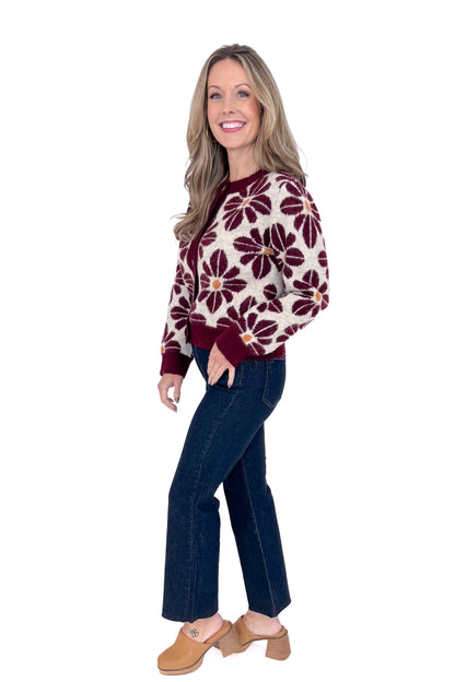 Side view of woman wearing Wine Floral Printed Button Up Cardigan by Entro with jeans against white studio background.
