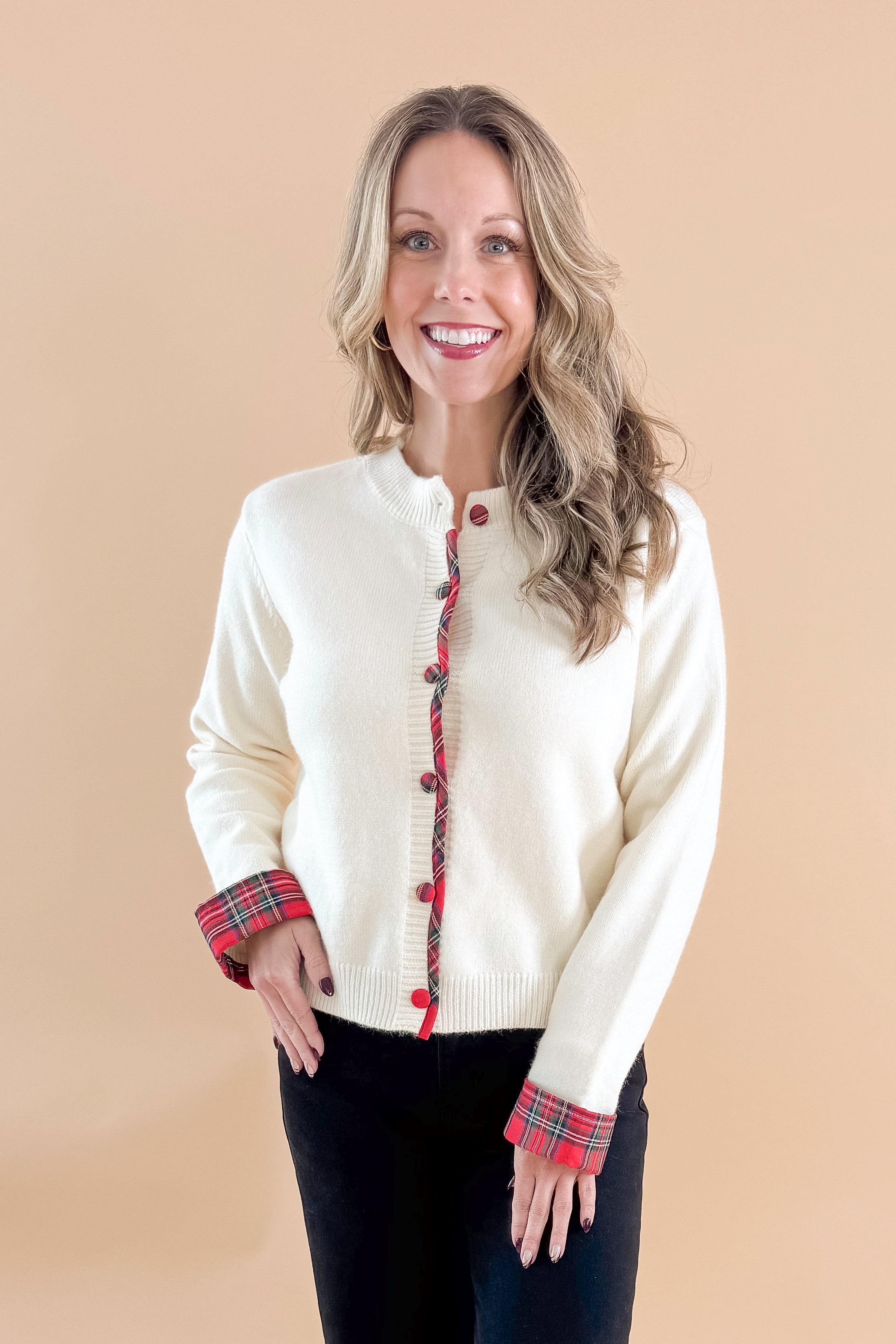Front view of woman wearing Cream With Tartan Detail Button Up Cardigan with jeans against tan studio background.