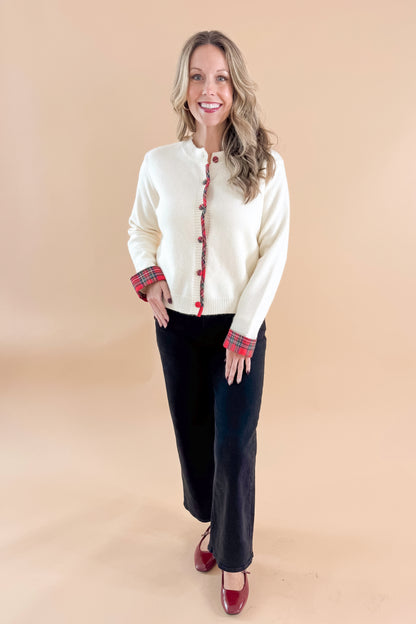 Front view of woman wearing Cream With Tartan Detail Button Up Cardigan with jeans against tan studio background.