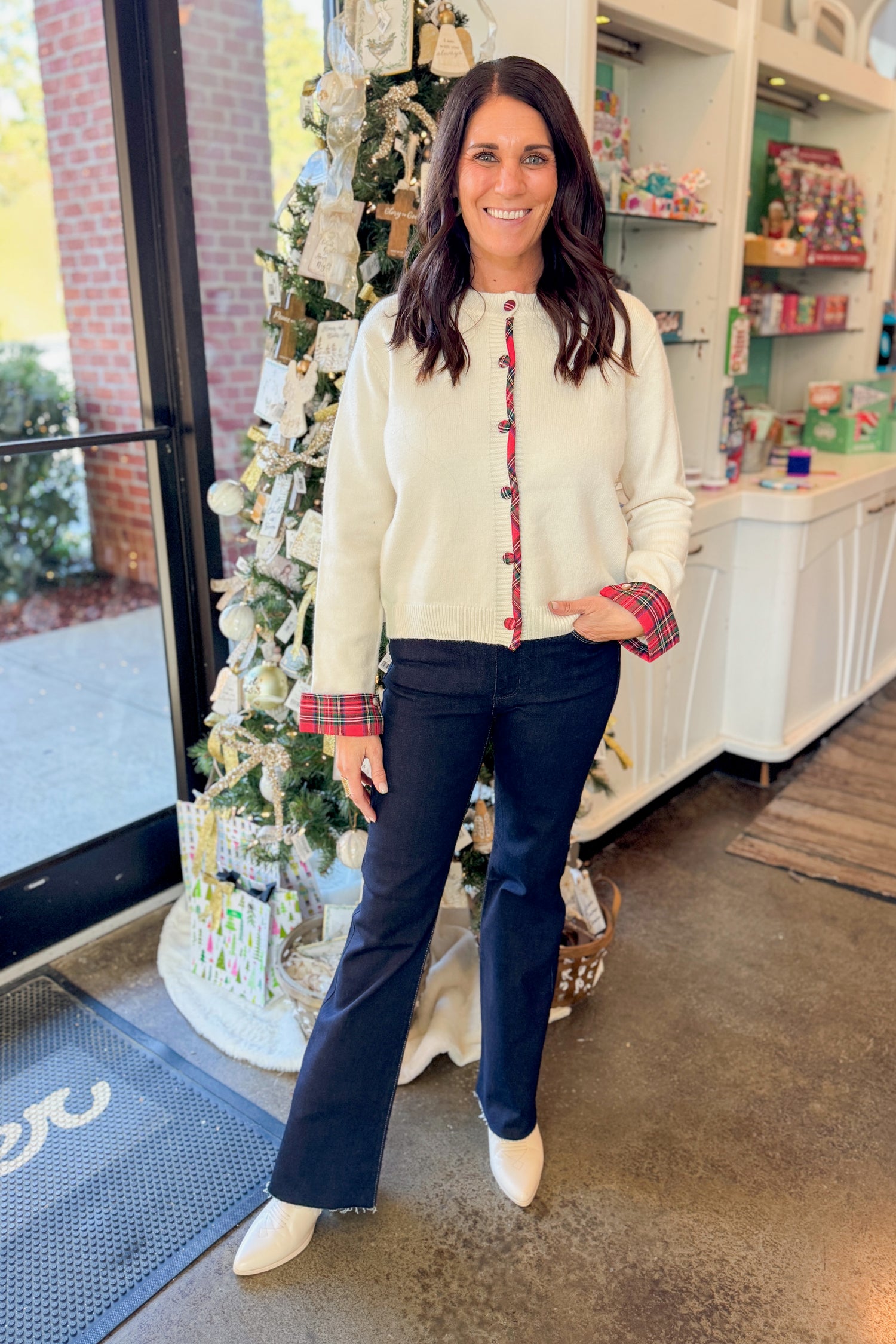 Front view of woman wearing Cream With Tartan Detail Button Up Cardigan with jeans at a boutique.