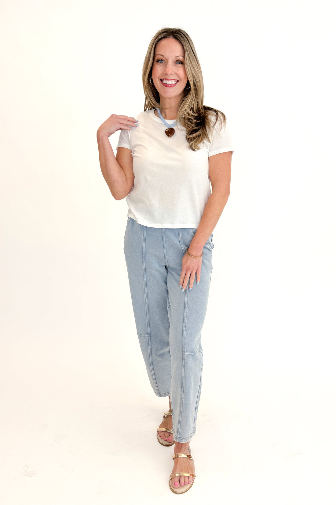 Front view of woman wearing white Z Supply top with Washed Light Blue Barrel Sweatpants against white studio background.