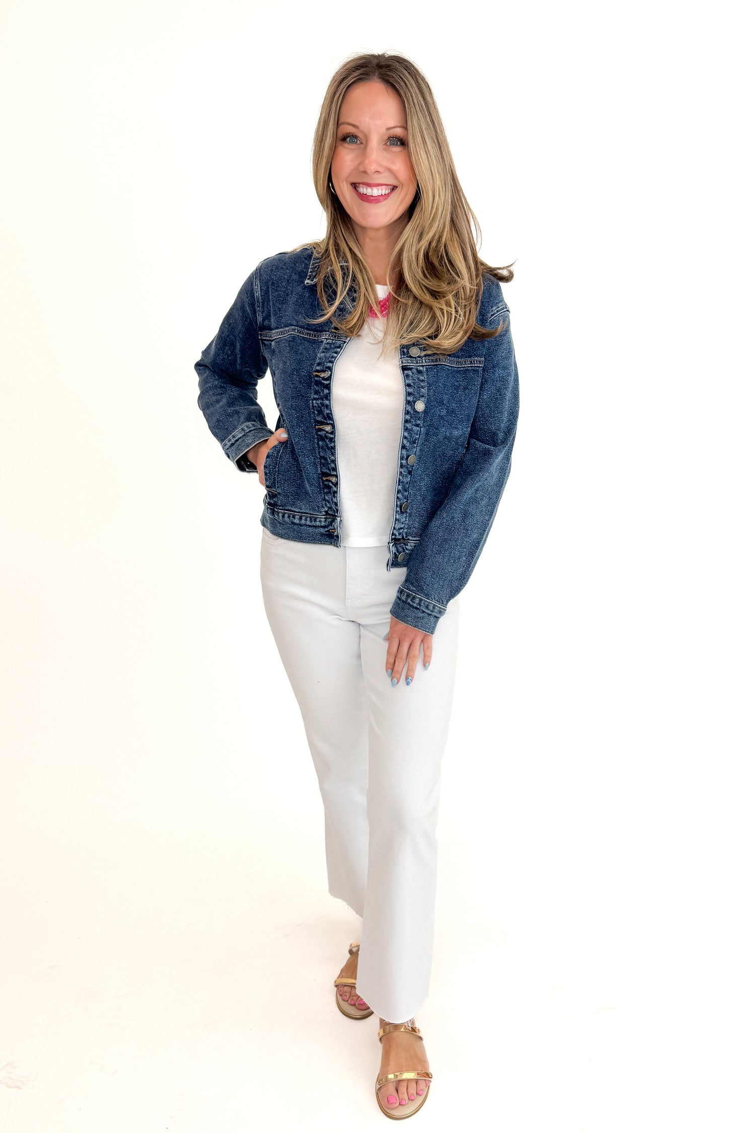 Front view of woman wearing Dark Wash Denim Jacket with jeans against white studio background.