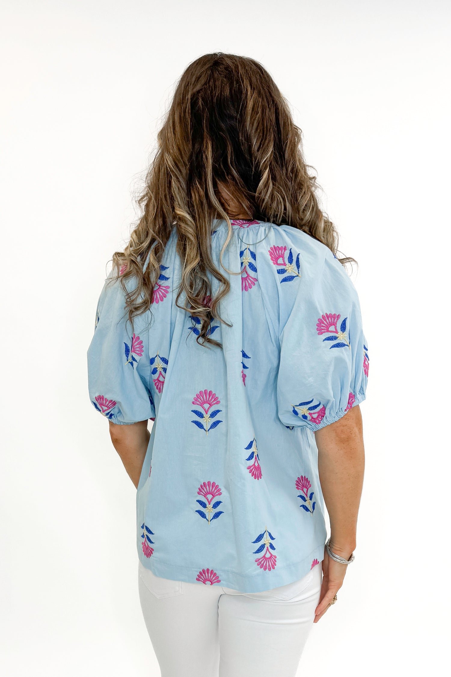 Backl view of woman wearing Blue &amp; Multi Floral Embroidered Top with jeans against white studio background.