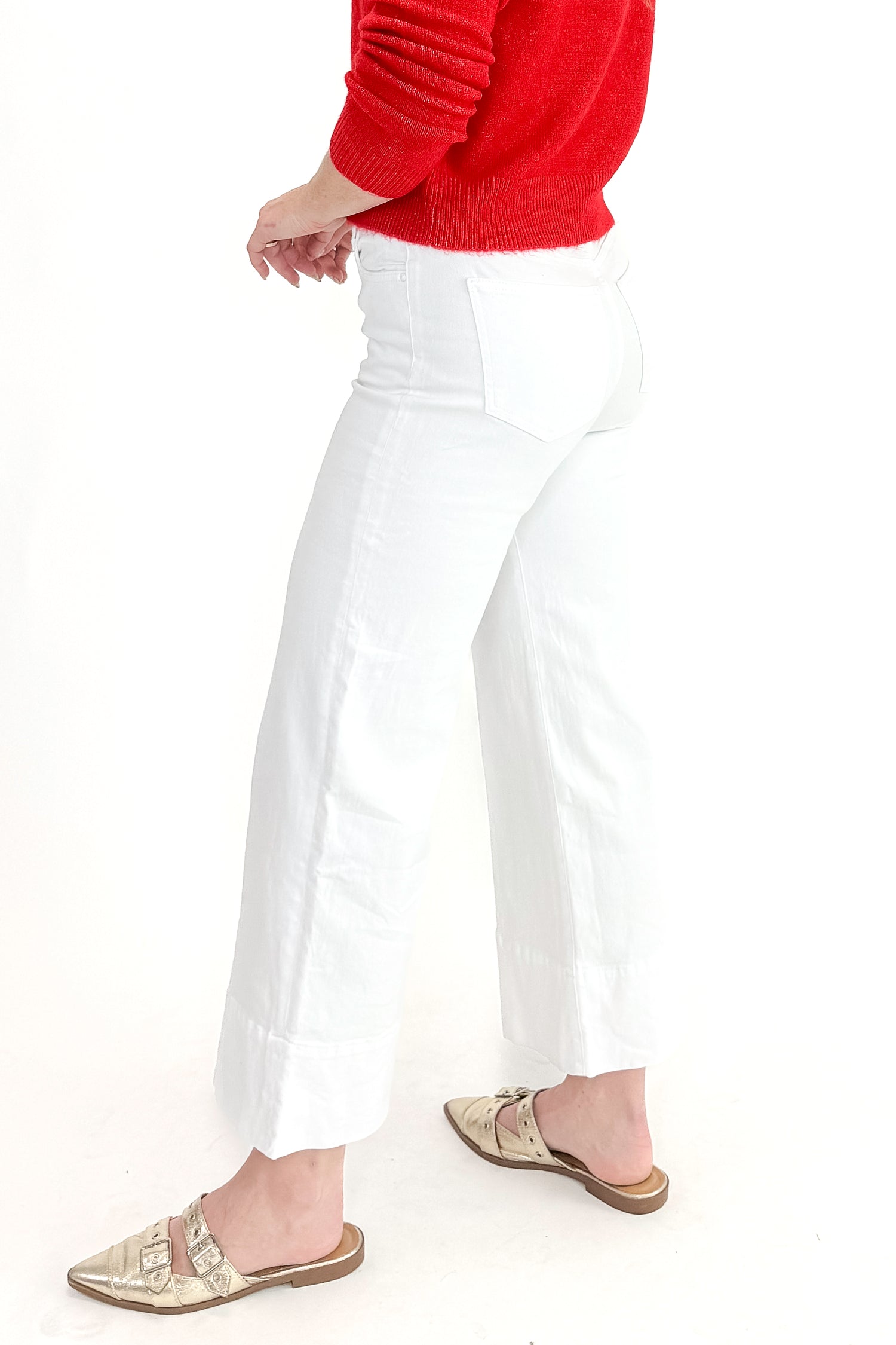 Side view of woman wearing top with Meg Optic White Pintuck Wide Leg Jeans by Kut from the Kloth against white studio background. 