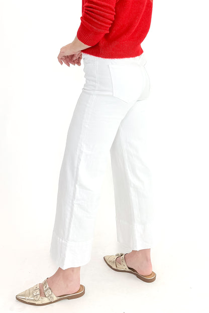 Side view of woman wearing top with Meg Optic White Pintuck Wide Leg Jeans by Kut from the Kloth against white studio background. 