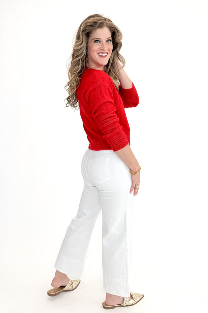 Side view of woman wearing top with Meg Optic White Pintuck Wide Leg Jeans by Kut from the Kloth against white studio background. 