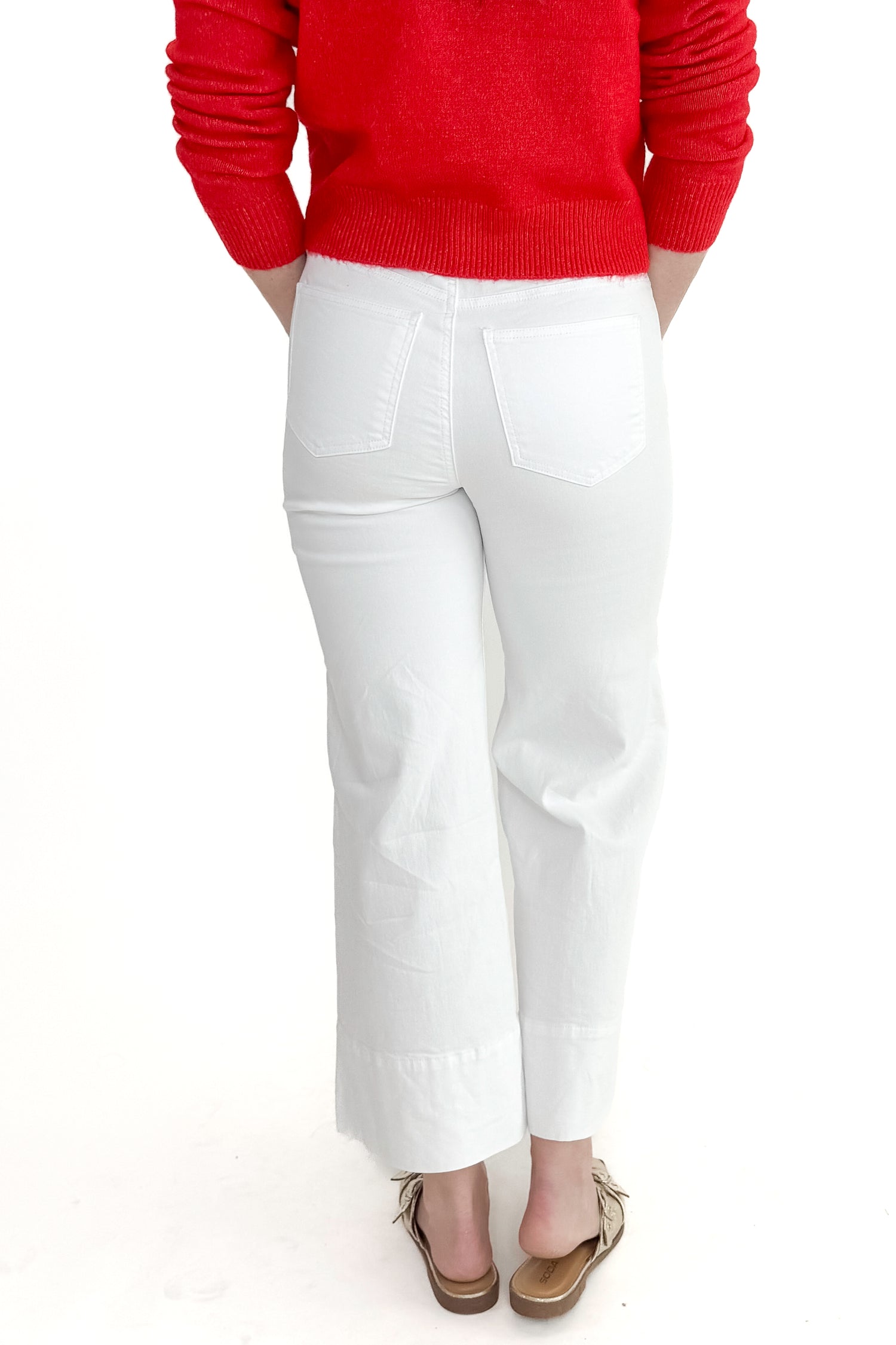 Back view of woman wearing top with Meg Optic White Pintuck Wide Leg Jeans by Kut from the Kloth against white studio background. 