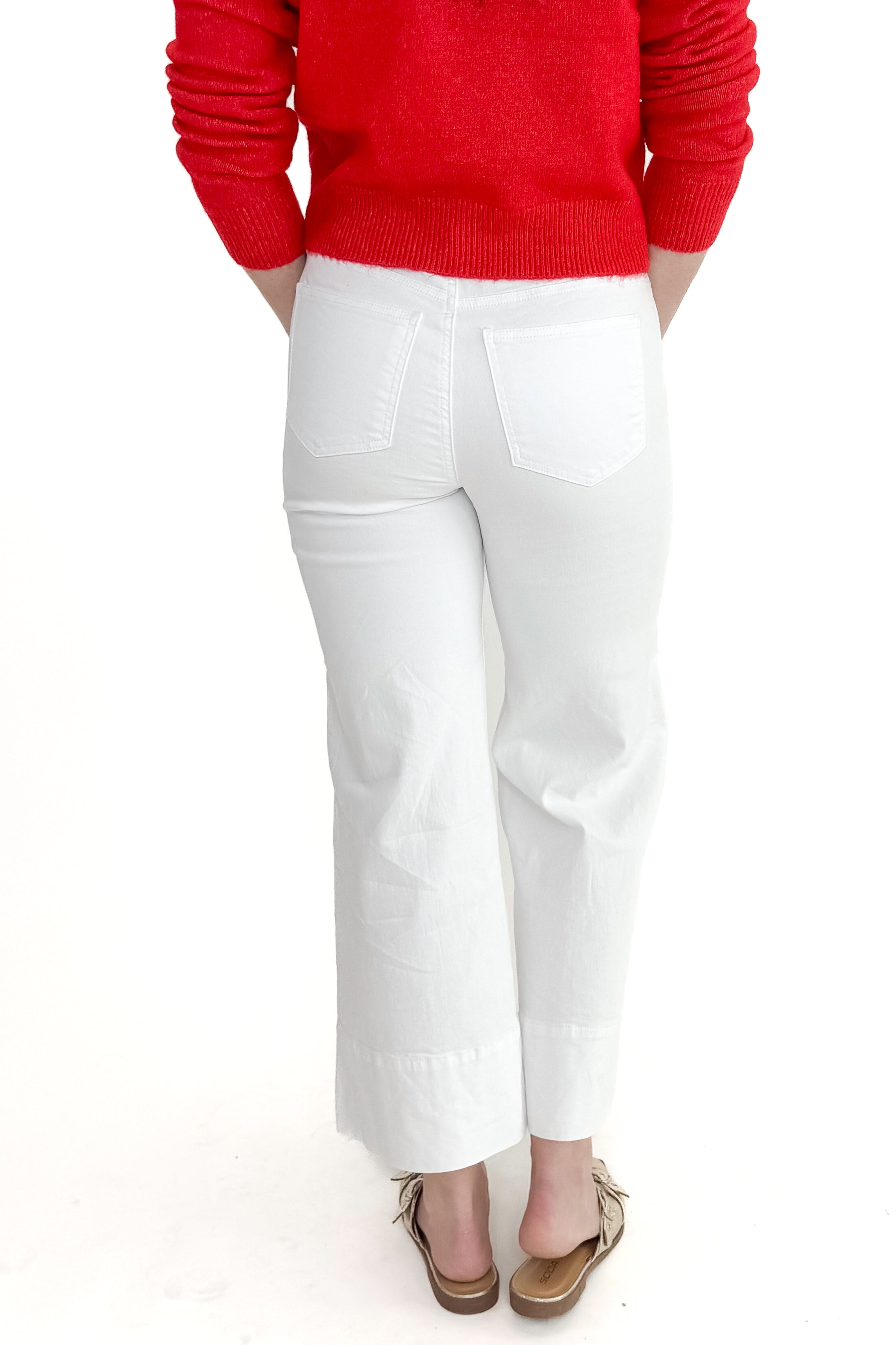 Back view of woman wearing top with Meg Optic White Pintuck Wide Leg Jeans by Kut from the Kloth against white studio background. 