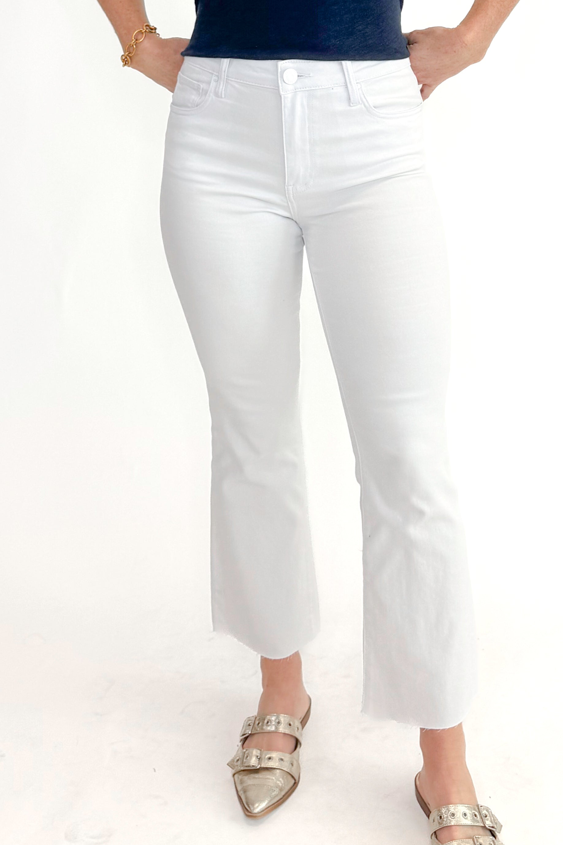 Front view of woman wearing top with Kelsey Optic White Ankle Flare Jeans by Kut from the Kloth against white studio background.