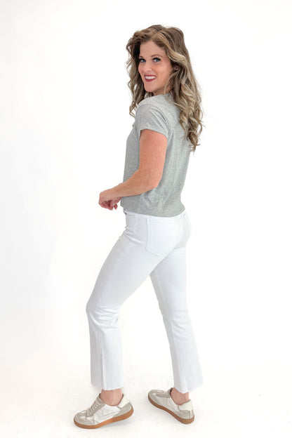 Side view of woman wearing top with Kelsey Optic White Ankle Flare Jeans by Kut from the Kloth against white studio background.
