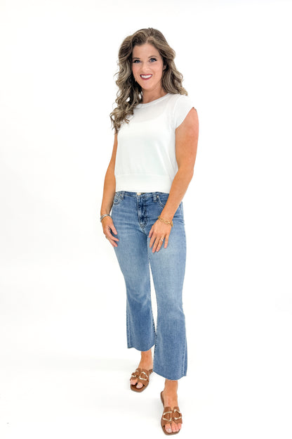 Front view of woman wearing Kelsey Ankle Flare Jeans In Medium Wash- Achievement by Kut from the Kloth with white sweater against white studio background.