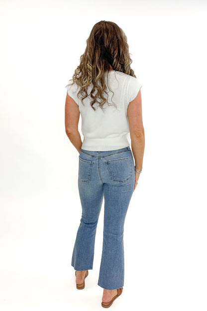 Back view of woman wearing Kelsey Ankle Flare Jeans In Medium Wash- Achievement by Kut from the Kloth with white sweater against white studio background.