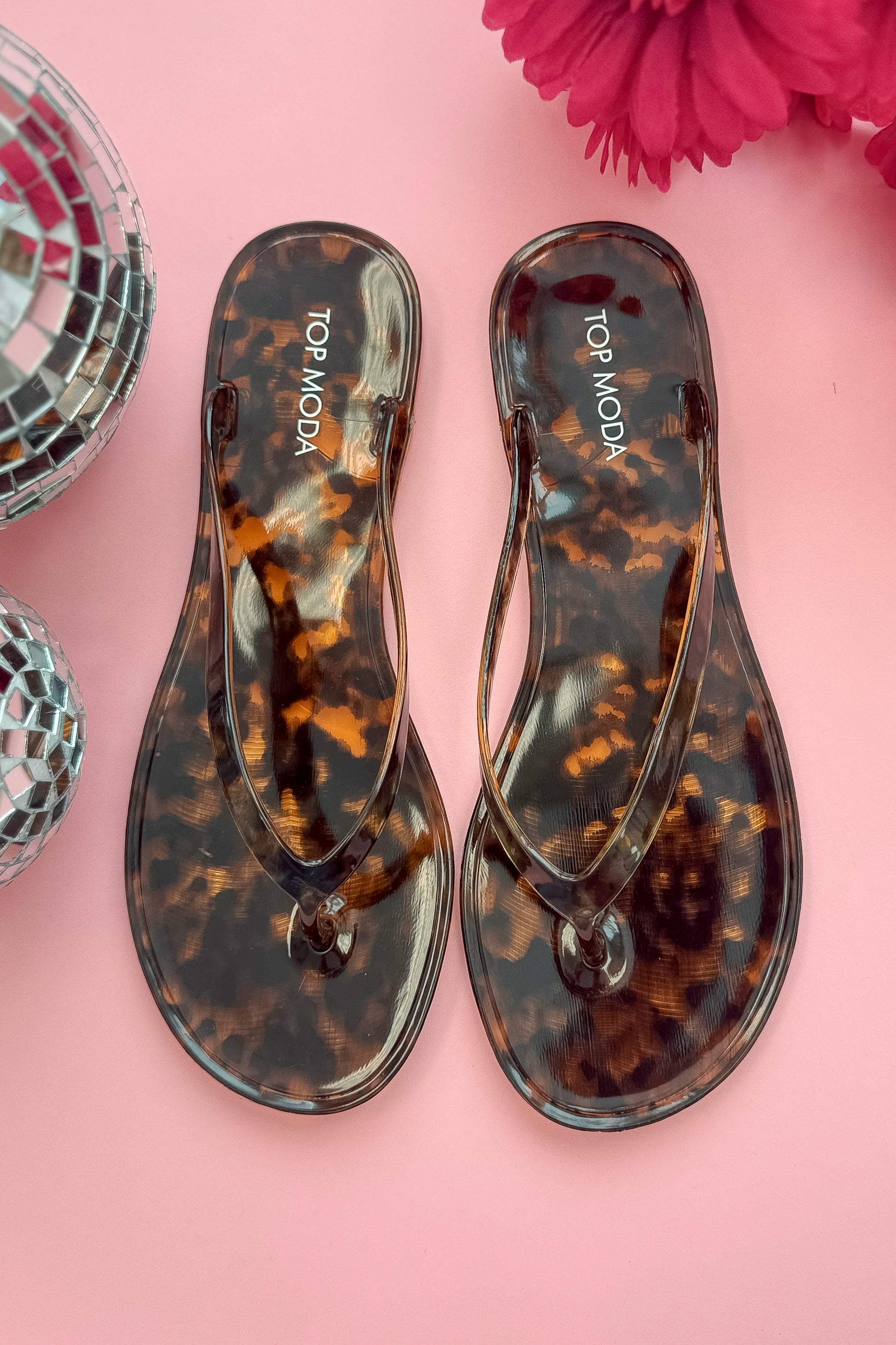 Kate- Tortoise Flip Flops against a pink background