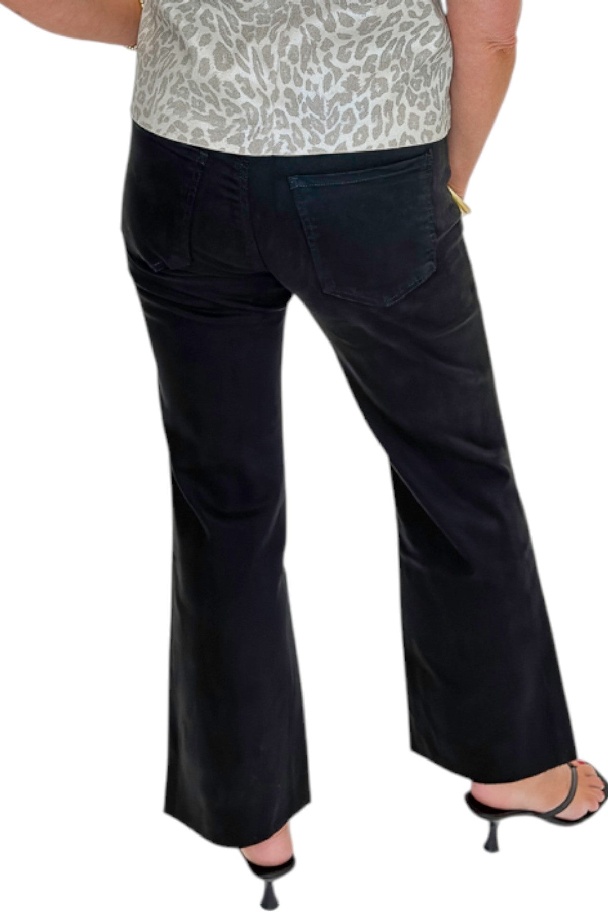 Back view of woman wearing Swagger Boutique’s Kelsey Ankle Flare Jeans In Black by Kut from the Kloth with top against white studio background.