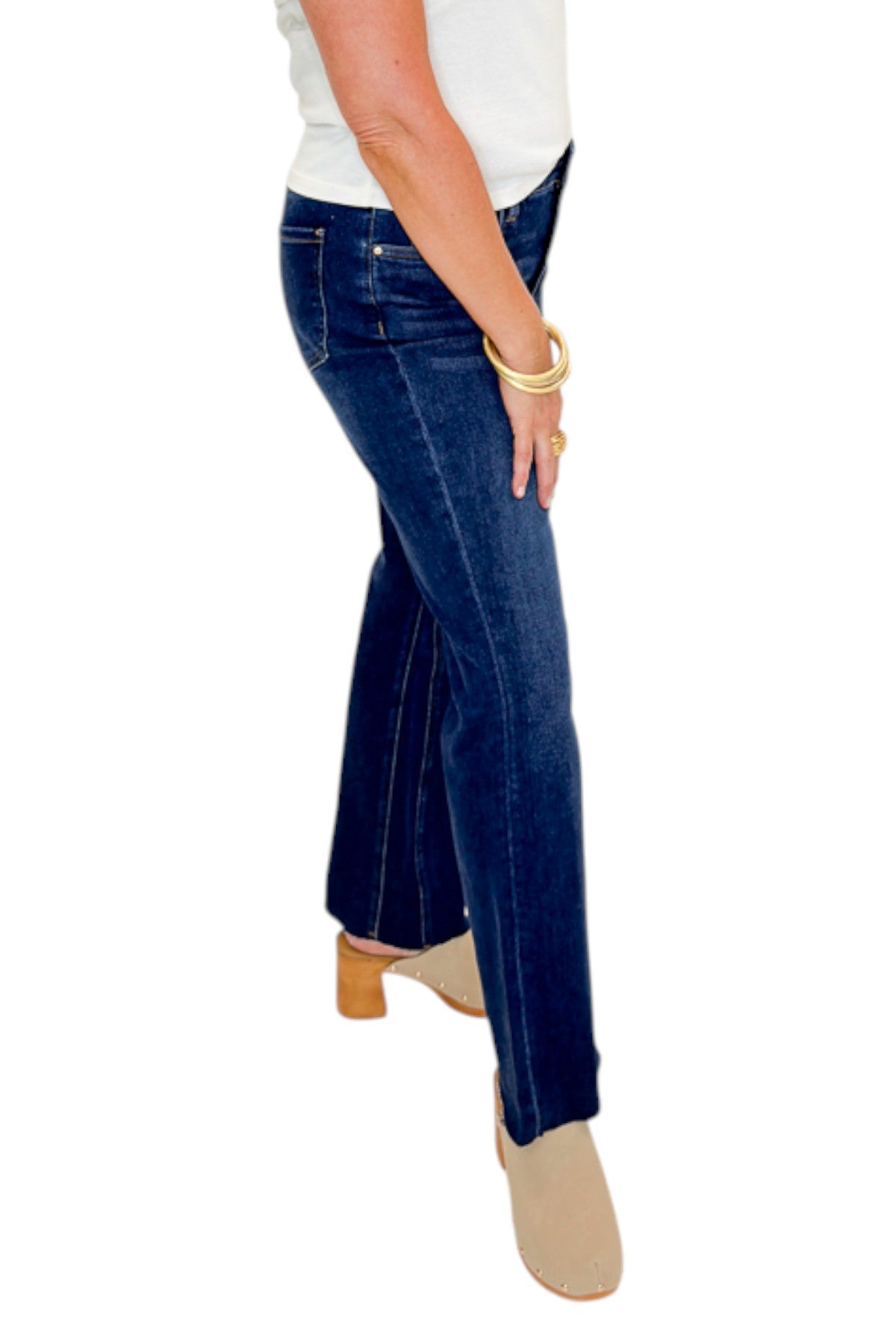 Side view of woman wearing Swagger Boutique’s Kelsey Ankle Flare Jeans In Dark Wash- Improve by Kut from the Kloth with top against white studio background.