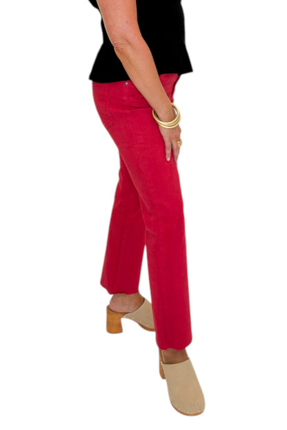 Side view of woman wearing Swagger Boutique’s Kelsey Ankle Flare Jeans In Ruby Red by Kut from the Kloth with black top against white studio background.