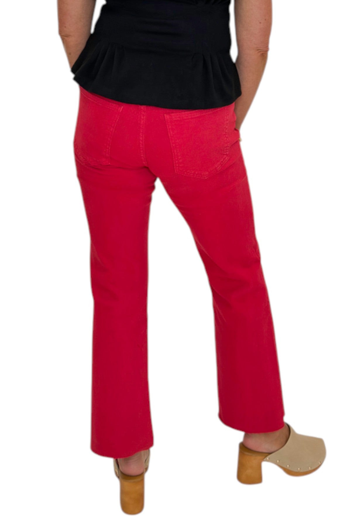 Back view of woman wearing Swagger Boutique’s Kelsey Ankle Flare Jeans In Ruby Red by Kut from the Kloth with black top against white studio background.