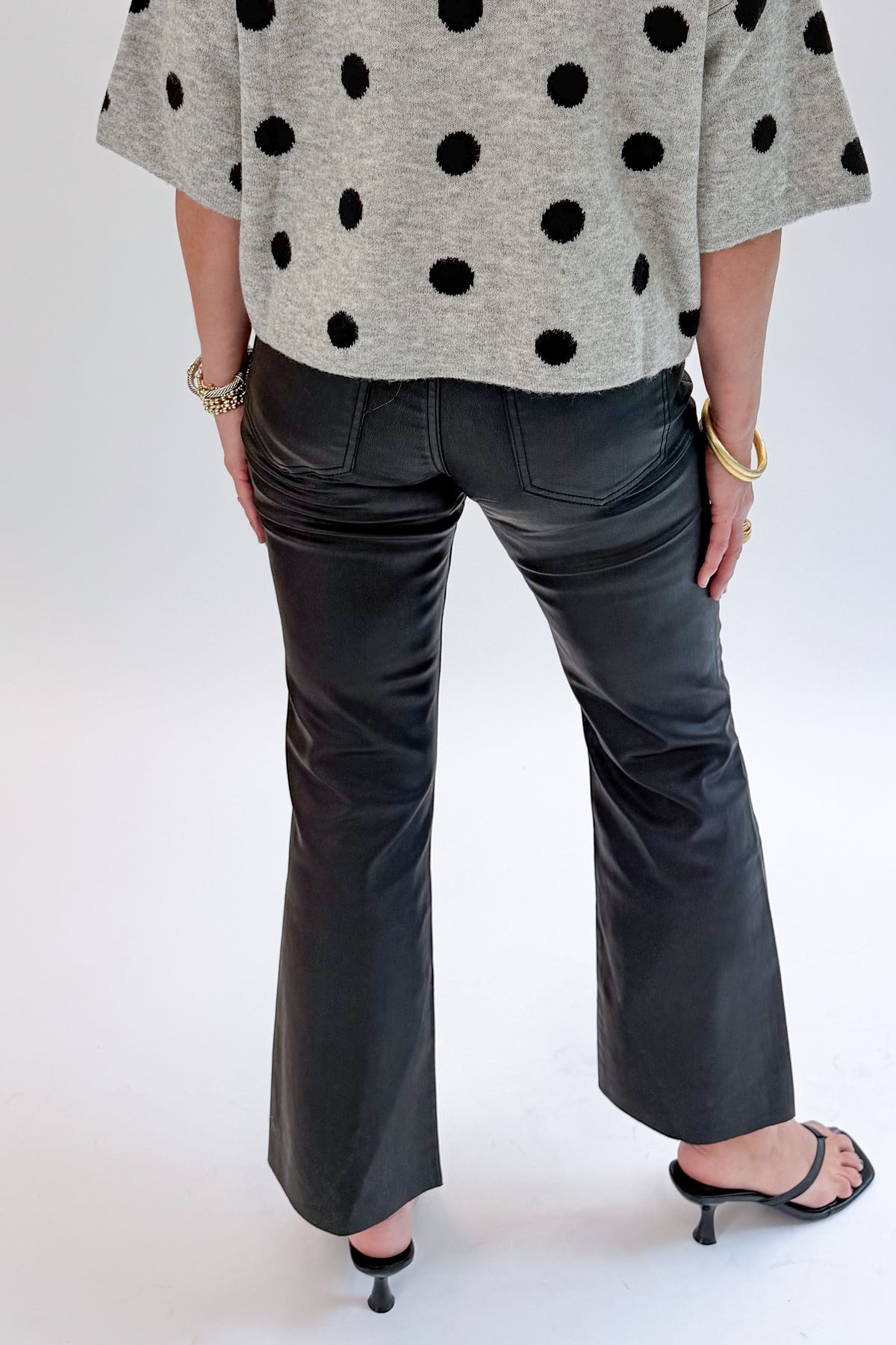 Back view of woman wearing Swagger Boutique’s Kelsey Coated Ankle Flare Jeans in Black by Kut from the Kloth against white studio background.