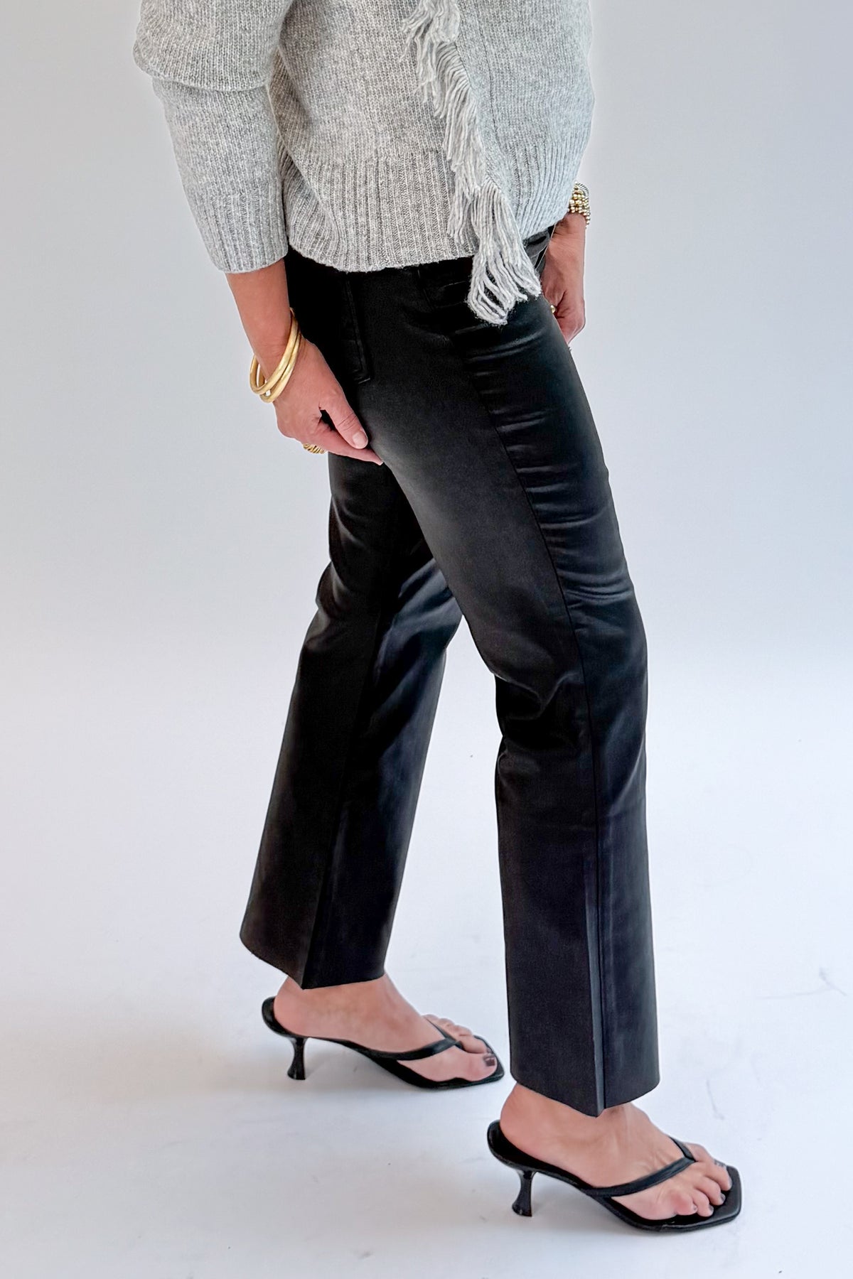 Side view of woman wearing Swagger Boutique’s Kelsey Coated Ankle Flare Jeans in Black by Kut from the Kloth against white studio background.
